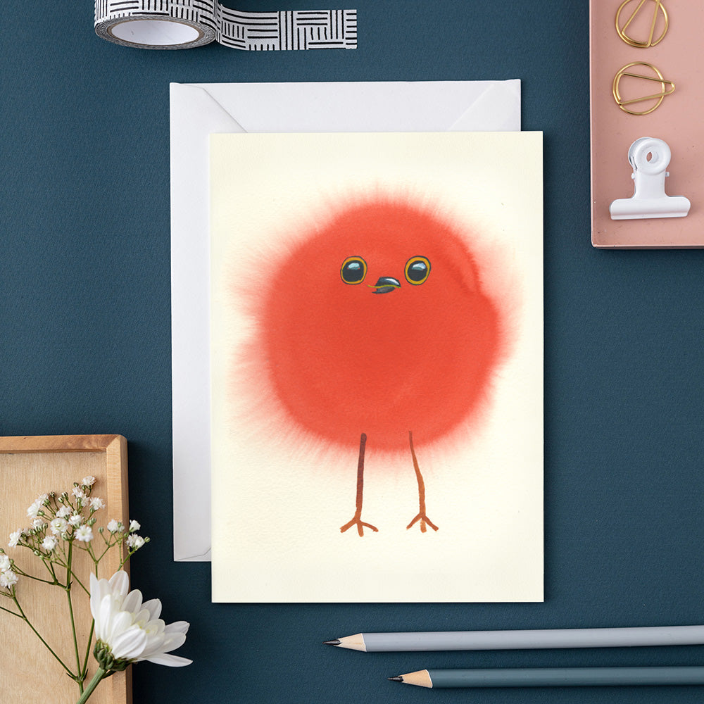 Greeting card with a funny Robin chick on a blue surface with stationery items.