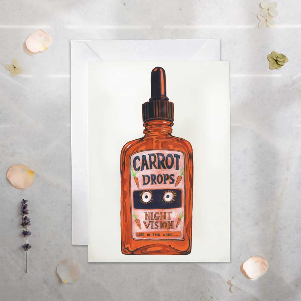 Greeting card with a bottle of 'Carrot Drops Night Vision' on a textured surface.