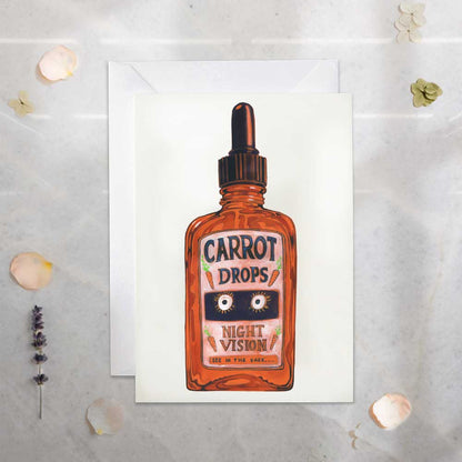 Greeting card with a bottle of 'Carrot Drops Night Vision' on a textured surface.