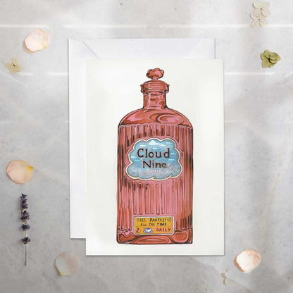 Greeting card with a bottle labeled 'Cloud Nine' on a textured surface.