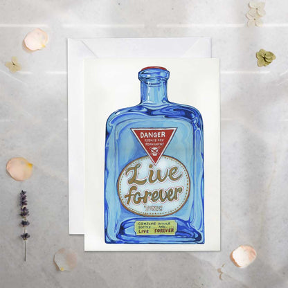 Greeting card- Live Forever Potion. Blue bottle design and 'Live Forever' text on a medical counter top